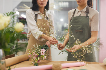 Cropped portrait of two creative young women arranging bouquets and floral compositions while working in flower shop, copy space