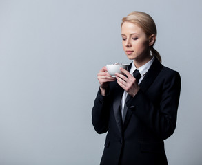 businesswoman in a classic black business suit with cup of coffee