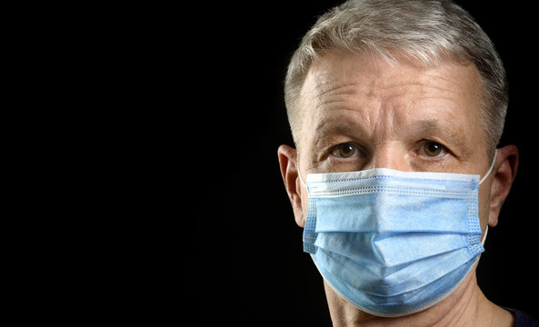 Portrait Of Man In Medical Mask Looking At Camera On Black Background. Copy Space