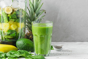 Blender for making smoothie and glass with green healthy smoothie detox made of spinach, pineapple,...