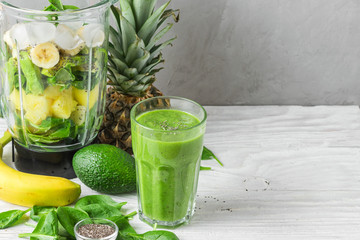 Glass of green smoothie detox with fresh juicy ingredients in blender for making healthy drink - obrazy, fototapety, plakaty