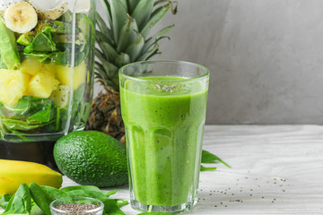 Glass with green healthy smoothie detox made of spinach, pineapple, avocado, banana and chia seeds...