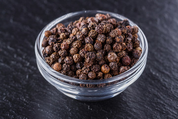 aromatic black pepper on a dark stone background