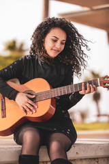 Brunette girl playing classical guitar