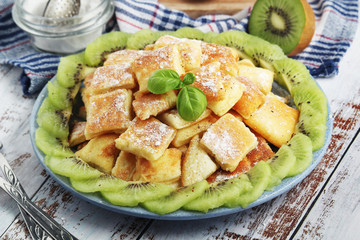 Austrian dessert Kaiserschmarrn served with sugar powder and kiwi fruit	
