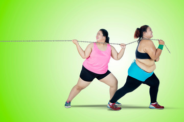 Two obese women pulling chain together