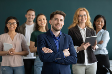 Group picture of successful millennial male boss CEO stand forefront pose with multiracial...