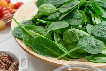 Baby spinach close up on a wooden plate. Salad ingredients close up.