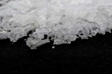 Maldon salt on black background macrophotography with slight defocus. Purity.