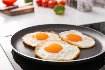 Frying pan with cooked eggs on stove