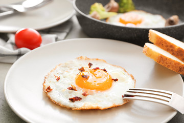 Plate with fried egg and bread on table, closeup