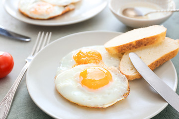 Plate with fried eggs and bread on table