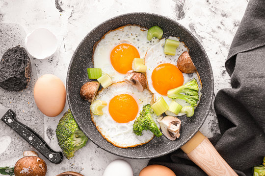 Frying Pan With Cooked Eggs And Vegetables On White Background