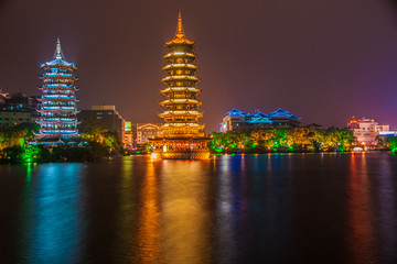 Guilin, China - May 9, 2010: Riyue Shuangta Cultural Park. Wide shot on the Twin Pagodas in Shanhu Lake, the silver and the gold, under pitch black night. Their lights reflected in water. 