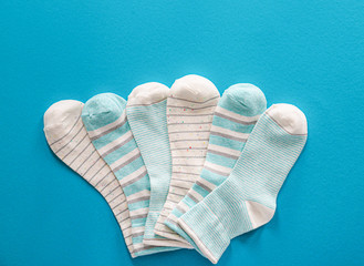 Different cotton socks on color background