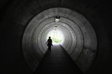  A lonely walker in a hollow tube with light at the end of the tunnel