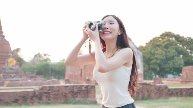 Close up Beautiful Asian Young Women taking photos with film camera in city Ayutthaya, Thailand In the evening. Concept Freedom woman having fun, traveling on holidays. Slow Motion
