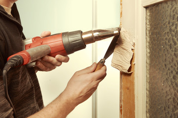 Man at home removing havy layer of old paint from door