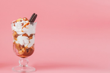 Sweet dessert in glass with biscuit and whipped cream on pink bsckground, selective focus and blank space