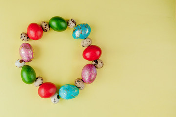 Top view painted eggs Easter Frame in circle shape on a yellow background. Copy space