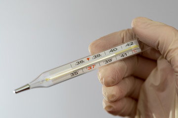 High body temperature. Mercury thermometer in the hands of a nurse. Body temperature measurement.