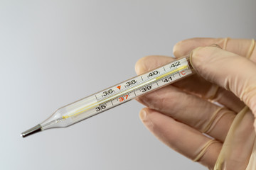 High body temperature. Mercury thermometer in the hands of a nurse. Body temperature measurement.