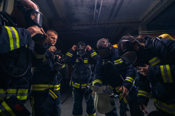 Group of firefighters standing inside the fire brigade wearing helmet and protective uniform