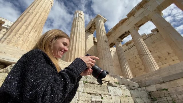 A pretty blonde woman photographer take pictures of columns of Parthenon Temple at the Acropolis of Athens