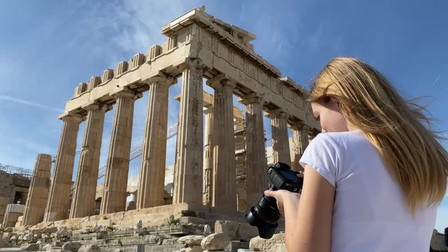 A pretty blonde woman photographer take pictures of the Parthenon Temple at the Acropolis of Athens