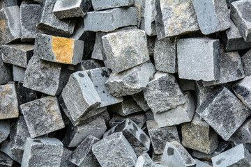 Pile of black natural stone cubes, outdoor pavement tiles. Broken road tiles