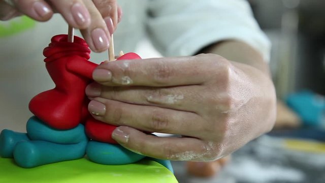 confectioner making figure from sugar paste fondant cake pastery