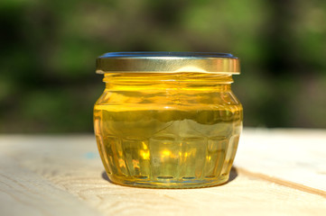small glass jar of honey on a wooden table