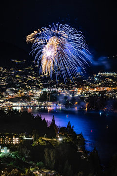 Wonderful Firework In Queenstown During Winter Festival. Lights Above The Lake With The City On The Background