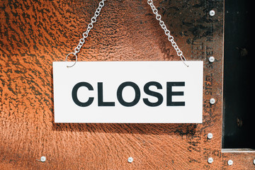 Close sign broad hanging on the  door in cafe with Grunge vintage rusty metal plate texture background. Business service and food concept. Vintage tone filter effect color style.