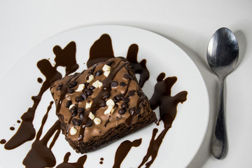 brownie bañado en chocolate en plato y fondo blanco