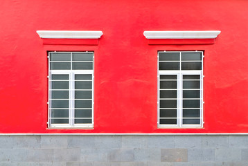 Red house, two barred windows, stone siding.