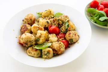 Gnocchi and chicken meatballs with pesto sauce, basil, tomatoes and nuts