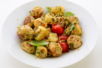 Gnocchi and chicken meatballs with pesto sauce, basil, tomatoes and nuts