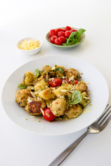 Gnocchi and chicken meatballs with pesto sauce, basil, tomatoes and nuts