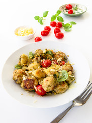 Gnocchi and chicken meatballs with pesto sauce, basil, tomatoes and nuts