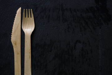 cuchillo y tenedor de madera en fondo negro, cuchillo y tenedor sustentable
