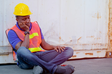 Technician man sit near the cargo container and act as sleepy and tired during working time.