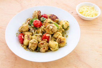 Gnocchi and chicken meatballs with pesto sauce, basil, tomatoes and nuts