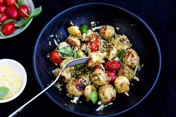 Gnocchi and chicken meatballs with pesto sauce, basil, tomatoes and nuts