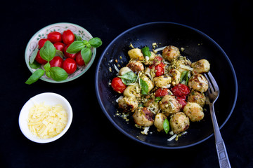 Gnocchi and chicken meatballs with pesto sauce, basil, tomatoes and nuts
