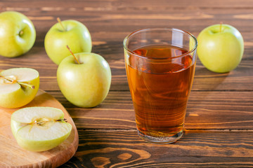 Healthy organic food and drink. Glass of apple juice and apples on wooden table.