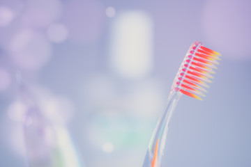Orange plastic toothbrush on a purple background with bubbles.