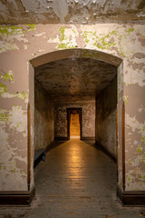 Hallway in an abandoned prison with a glowing light coming from a distant room.
