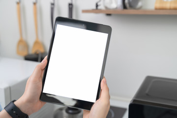 Close-up of hand holding digital tablet at home in kitchen.