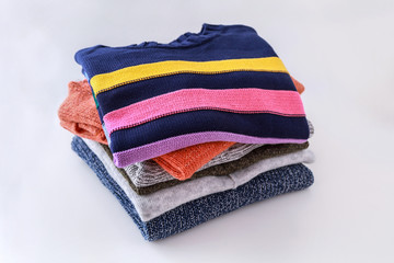 Stack of color sweaters on white background.. Household and laundry concept. 
